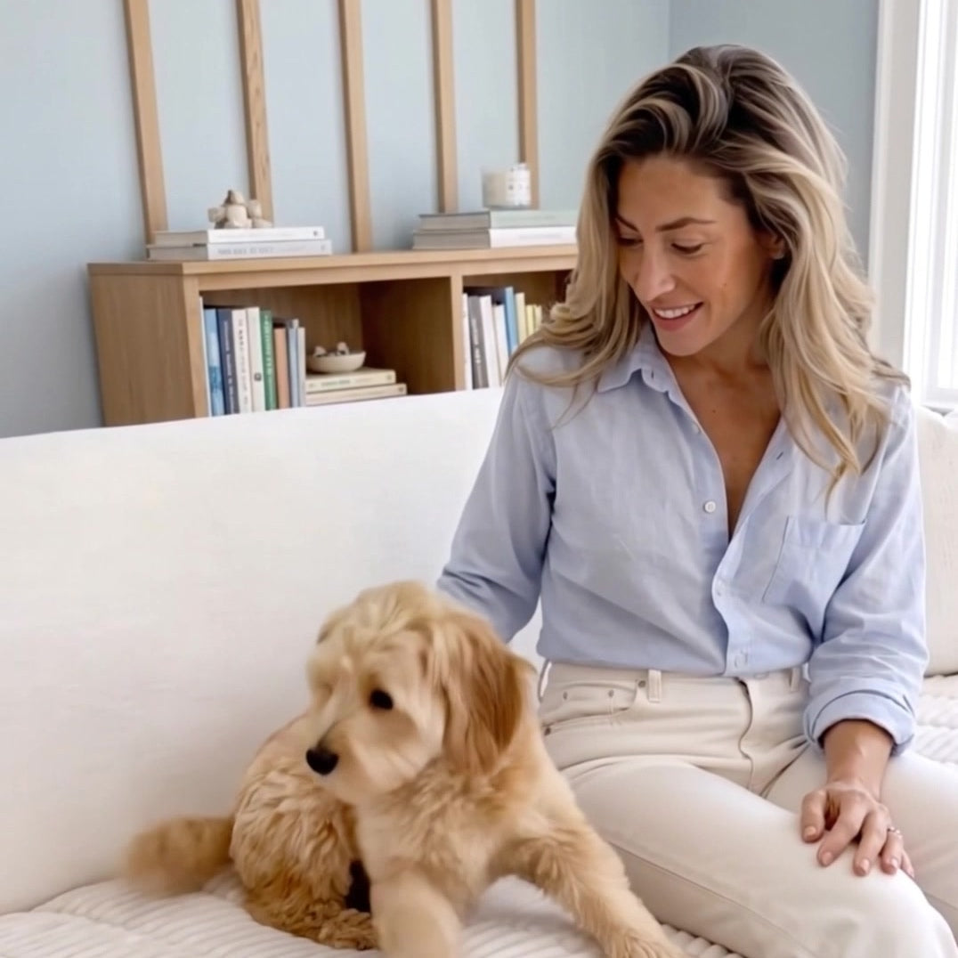 Small dog relaxing beside a woman on a white plush ribbed seat cover